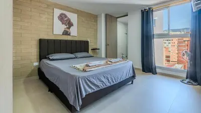 a bedroom with a large bed with a brick wall at Apartamento en Laureles con piscina y parquedero 802 in Medellín