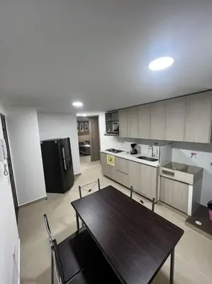 a kitchen with a wooden table and a black refrigerator at Exclusivo apartamento con piscina y parqueadero 602 in Medellín
