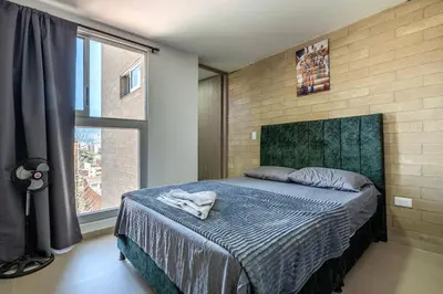 a bedroom with a bed and a large window at Apartamento en Laureles 2BR con rooftop y piscina 702 in Medellín