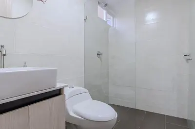 a white bathroom with a toilet and a shower at Apartamento en Laureles 2BR con rooftop y piscina 702 in Medellín
