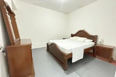 a bedroom with a bed with white sheets and a dresser at HOSPEDAJE LAURa in Medellín