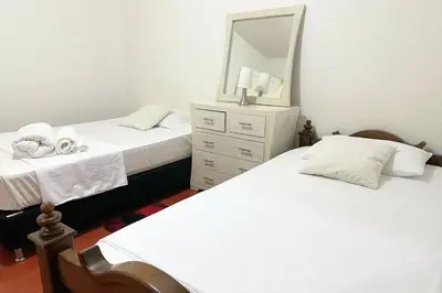 two beds in a bedroom with a mirror and a dresser at HOSPEDAJE LAURa in Medellín