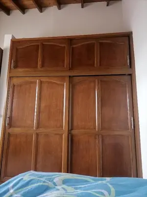 a wooden closet with wooden doors in a bedroom at Cuarto con cuarto de baño y terraza in Medellín
