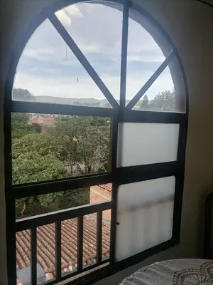 an arched window in a bedroom with a view at Cuarto con cuarto de baño y terraza in Medellín