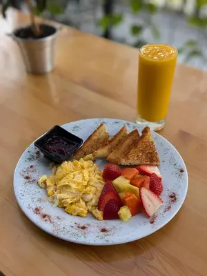 a plate of breakfast food with toast fruit and a glass of orange juice at Firenze Lofts in Medellín