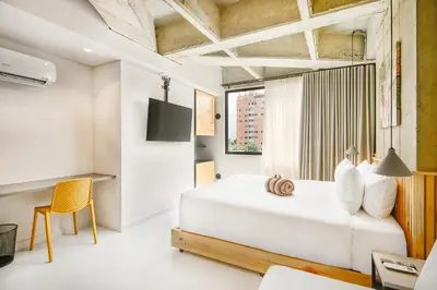 a bedroom with a white bed and a yellow chair at Firenze Lofts in Medellín