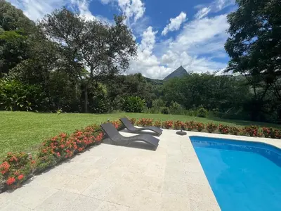 a swimming pool with two chairs next to a garden at Finca La Siria vista Cerro Tusa in Amagá