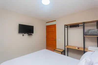 a bedroom with a bed and a tv on the wall at Hotel Tropical San Jeronimo in San Jerónimo