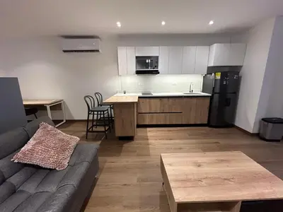 a living room with a couch and a kitchen at Acogedor Apto a pasos del metro de Medellín zona centro in Medellín