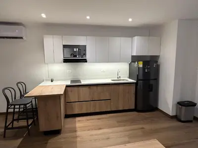 a kitchen with white cabinets and a black refrigerator at Acogedor Apto a pasos del metro de Medellín zona centro in Medellín