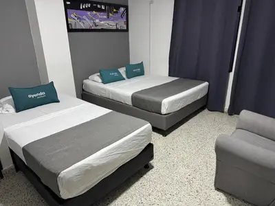 two beds and a chair in a small room at Hotel JC 43 in Medellín