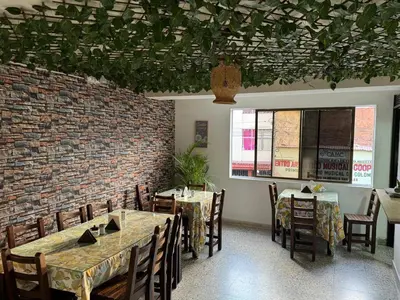 a dining room with tables and chairs and a brick wall at Hotel JC 43 in Medellín