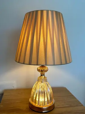 a gold table lamp sitting on a wooden table at Fénix in Marinilla