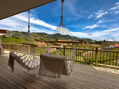 a porch with two hammocks on a deck with a view at Fénix in Marinilla