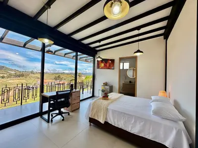 a bedroom with a bed and a desk and a large window at Fénix in Marinilla