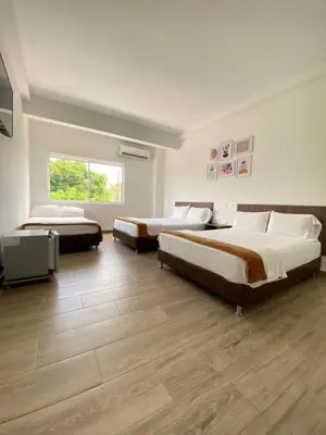 two beds in a room with wooden floors at Hotel FENIX in Doradal
