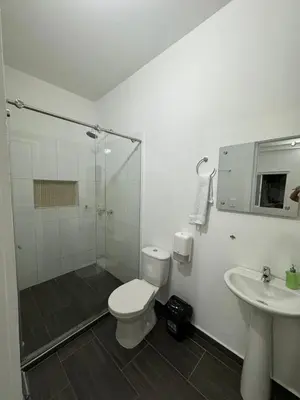 a bathroom with a shower and a toilet and a sink at Hotel FENIX in Doradal
