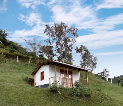 a small white house on a grassy hill at Ancestral Cabaña in San Vicente
