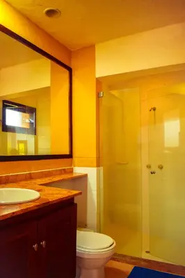 a bathroom with a toilet and a glass shower at Villas Mamilú, entrada y salida 100 por ciento flexible in Santa Fe de Antioquia