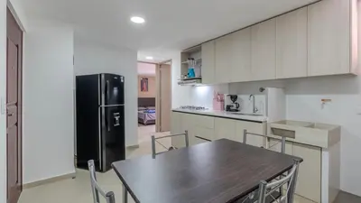 a kitchen with a wooden table and a black refrigerator at Apartamento en laureles con piscina y parqueadero 402 in Medellín