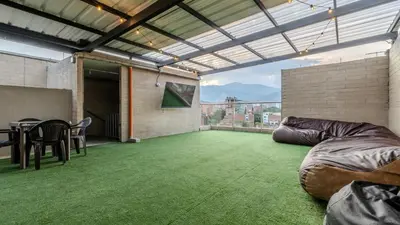 a large patio with a table and chairs on a green floor at Apartamento en laureles con piscina y parqueadero 402 in Medellín