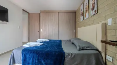 a bedroom with a bed with a blue blanket on it at Apartamento en laureles con piscina, parqueadero 302 in Medellín