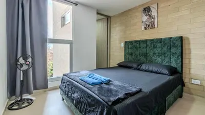 a bedroom with a bed and a lamp and a window at Apartamento 2BR Parqueadero y Piscina 202 in Medellín