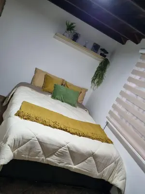 a bedroom with a bed with a green pillow on it at Pedacito de cielo in San Antonio de Prado