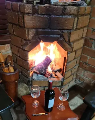 a fireplace with two wine glasses on a table at Pedacito de cielo in San Antonio de Prado