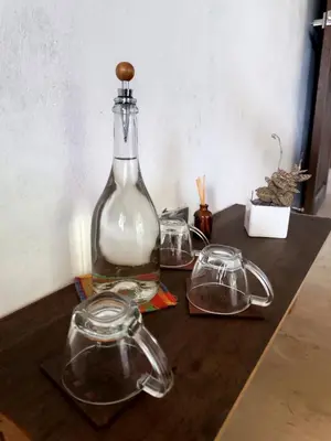 a bottle and two glasses on a wooden table at Bosque Místico in San Carlos