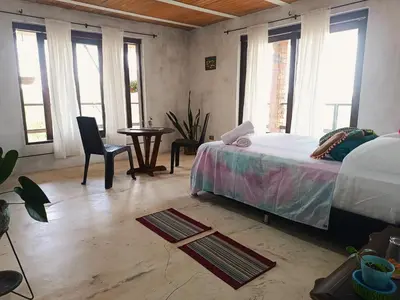 a bedroom with a bed and a table and windows at Bosque Místico in San Carlos