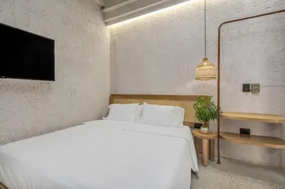a bedroom with a white bed and a flat screen tv at Botánica Casa Hotel Manila by HOUSY in Medellín