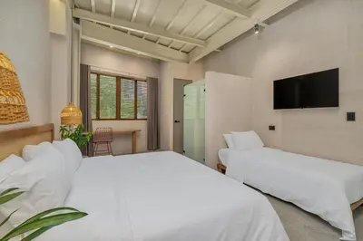 a bedroom with two beds and a flat screen tv at Botánica Casa Hotel Manila by HOUSY in Medellín