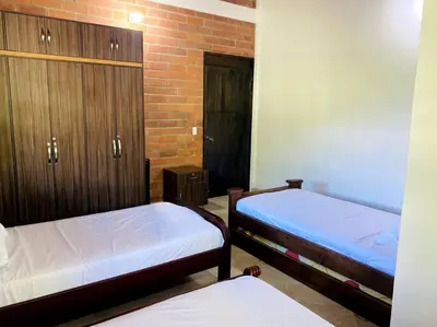 a bedroom with two beds and a brick wall at Finca con Piscina Privada in San Jerónimo
