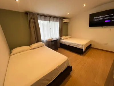 a room with two beds and a flat screen tv at Loft Recuerdos de mi tierra in Medellín