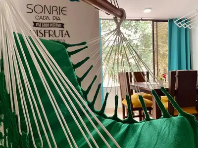 a green hammock in a room with a table at explora la magia de laureles in Medellín