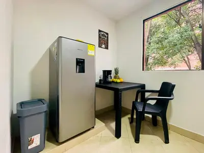 a refrigerator and a table with a chair in a room at explora la magia de laureles in Medellín