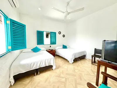 a bedroom with two beds and blue shuttered windows at Plaza Blanca in Doradal