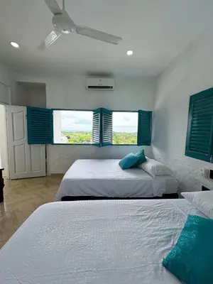 two beds in a bedroom with blue shuttered windows at Plaza Blanca in Doradal