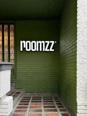 a green brick wall with a sign on it at Hotel Boutique Roomzz Laureles in Medellín