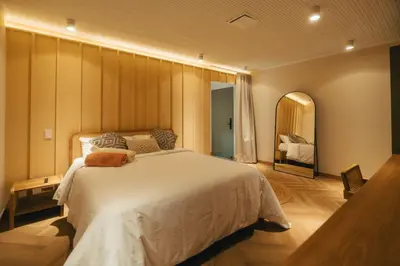 a bedroom with a large white bed and a mirror at Hotel Boutique Roomzz Laureles in Medellín