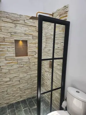 a bathroom with a toilet and a stone wall at Acogedor apartaloft El Poblado in Medellín