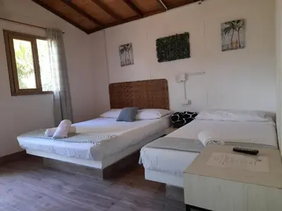 a bedroom with two beds and a table and a window at Finca Hotel La Estancia Santa Fe in Santa Fe de Antioquia