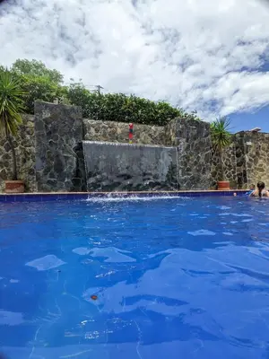 a swimming pool with blue water and a stone wall at Hotel Bosque Blue in San Jerónimo