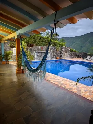 a hammock hanging from a porch next to a swimming pool at Hotel Bosque Blue in San Jerónimo