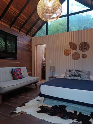 a bedroom with a bed and a couch and a chandelier at Cabaña Momotus II in Concepción