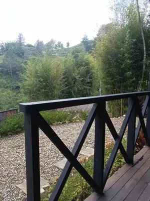 a wooden railing on a deck with trees in the background at Cabaña Momotus II in Concepción