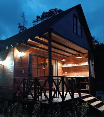 a log cabin with a deck at night at Cabaña Momotus II in Concepción