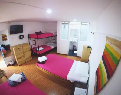 a bedroom with a bed with a pink blanket at Hostal de la 57 in Manizales