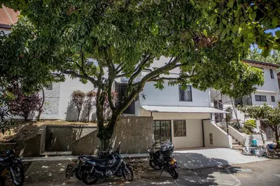 two motorcycles parked next to a tree in front of a house at Apartahotel Castellana in América